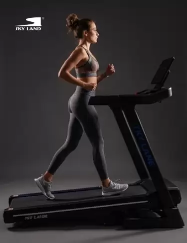 Woman walking on a SKY LAND treadmill during a cardio workout, highlighting smooth performance and fitness training.