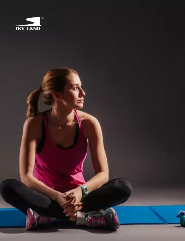Woman sitting on a SKY LAND exercise mat after a workout, ideal for stretching, yoga, recovery, and fitness routines.
