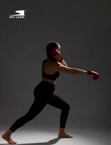 Woman performing boxing training with SKY LAND boxing gloves, improving strength, endurance, coordination, and fitness.